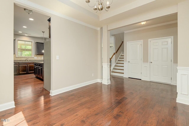 unfurnished room featuring a tray ceiling, an inviting chandelier, dark hardwood / wood-style floors, and crown molding