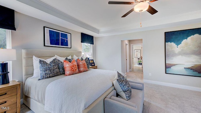 carpeted bedroom with ceiling fan, crown molding, and a tray ceiling