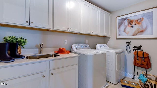 clothes washing area with cabinets, sink, and washer and clothes dryer