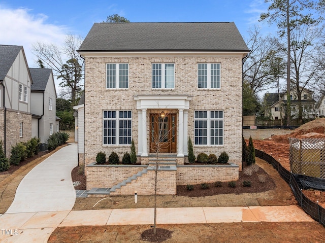 view of front of home featuring brick siding and a shingled roof