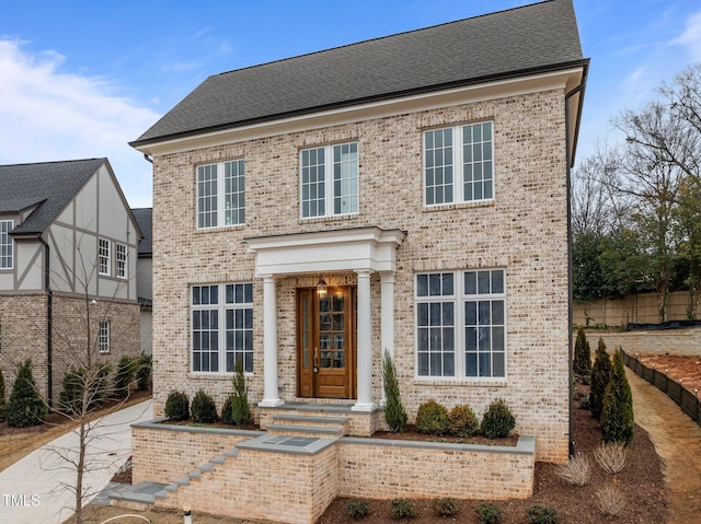 view of front facade with a shingled roof and brick siding