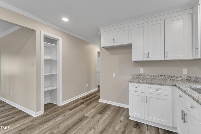 1518 Parks Village Rd, Zebulon, NC 27597 - kitchen featuring crown molding, light wood-style floors, white cabinets, baseboards, and light stone countertops