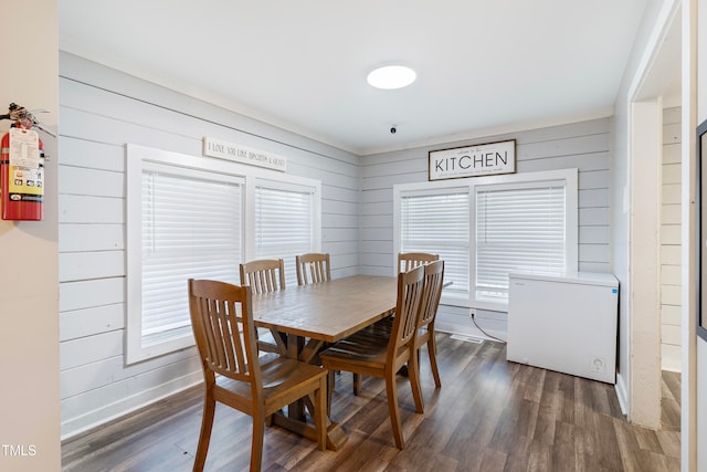 dining area featuring wood walls and dark hardwood / wood-style floors