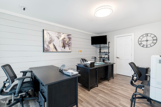 office with light wood-type flooring and wooden walls