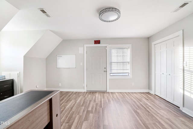 unfurnished office with lofted ceiling and light wood-type flooring