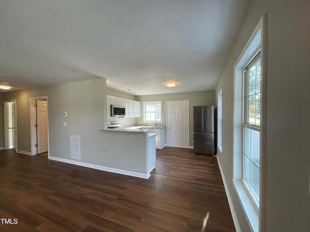 kitchen with white cabinets, kitchen peninsula, appliances with stainless steel finishes, and dark hardwood / wood-style flooring