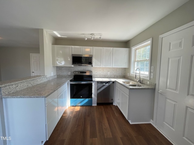 kitchen with light stone counters, stainless steel appliances, dark hardwood / wood-style flooring, white cabinets, and kitchen peninsula