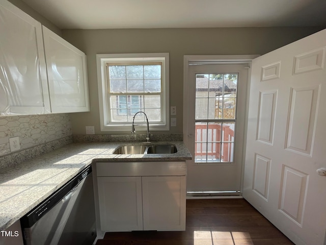 kitchen with dark hardwood / wood-style flooring, sink, tasteful backsplash, stainless steel dishwasher, and white cabinetry