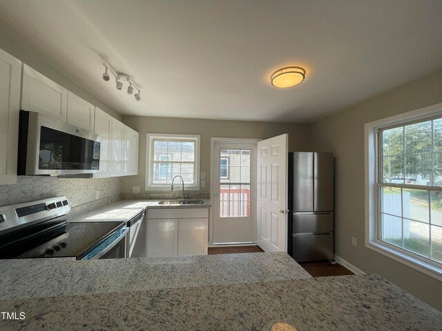 kitchen with white cabinets, appliances with stainless steel finishes, sink, and light stone countertops