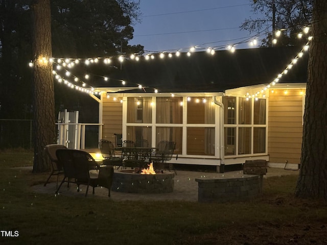 back of house featuring a sunroom, a patio, and a fire pit