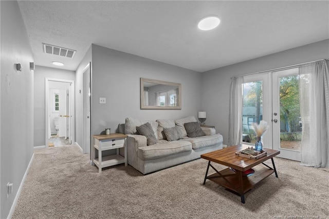 carpeted living room with french doors and a textured ceiling