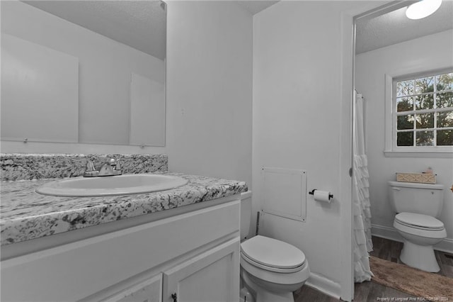 bathroom featuring hardwood / wood-style flooring, vanity, toilet, and a textured ceiling