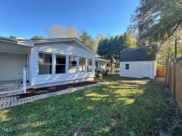 view of side of property with a storage unit, a deck, and a yard