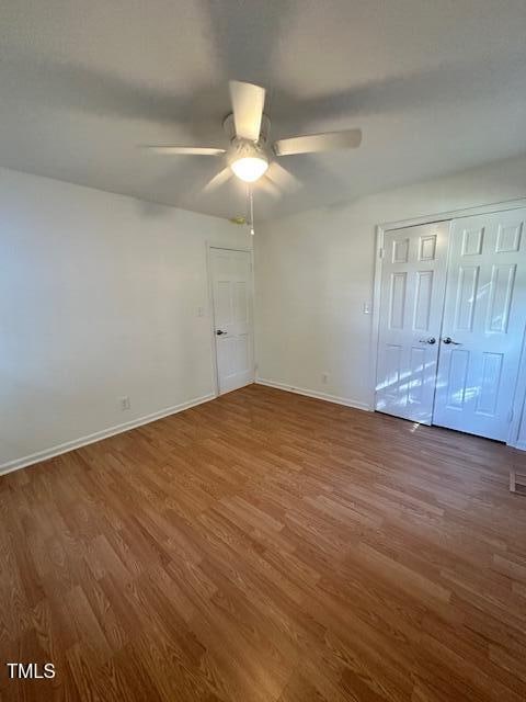 unfurnished bedroom featuring a closet, hardwood / wood-style flooring, and ceiling fan