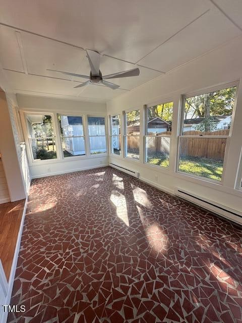 unfurnished sunroom with ceiling fan and a baseboard heating unit