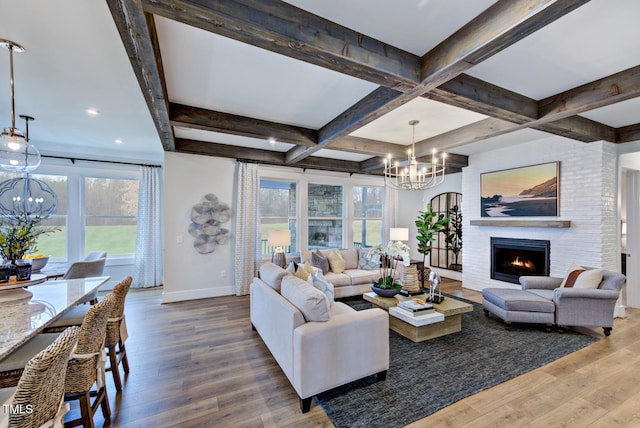 living room featuring coffered ceiling, beamed ceiling, a notable chandelier, hardwood / wood-style flooring, and a fireplace