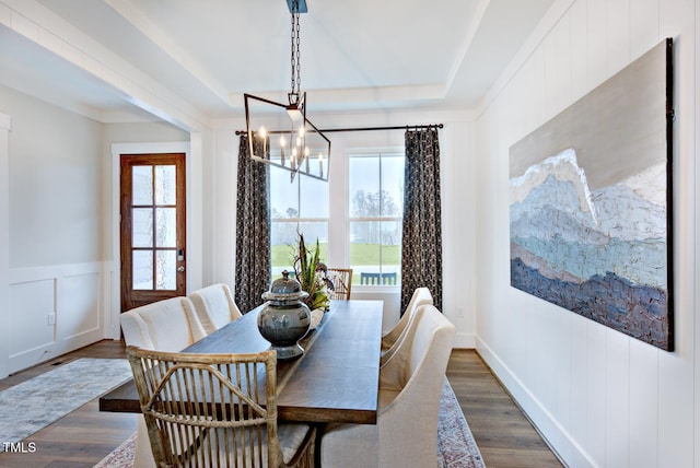 dining area featuring a raised ceiling, an inviting chandelier, a wealth of natural light, and dark hardwood / wood-style flooring