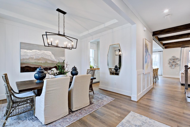 dining space featuring an inviting chandelier, beam ceiling, and light hardwood / wood-style floors