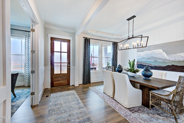 dining room with dark wood-type flooring, beam ceiling, and a notable chandelier