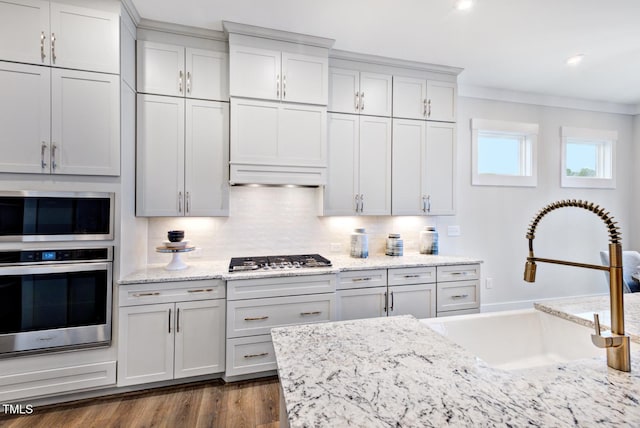 kitchen with sink, tasteful backsplash, ornamental molding, dark hardwood / wood-style flooring, and stainless steel appliances