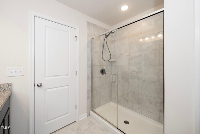 bathroom with tile patterned flooring, walk in shower, and vanity