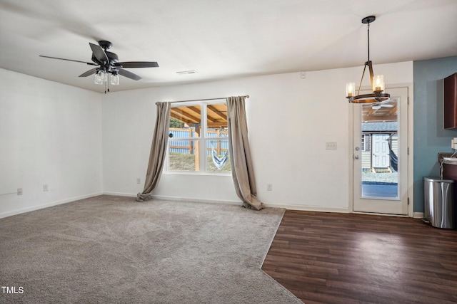 interior space featuring dark wood-type flooring and ceiling fan with notable chandelier