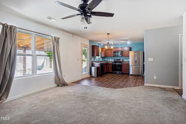 unfurnished living room featuring sink, ceiling fan with notable chandelier, track lighting, and dark hardwood / wood-style floors