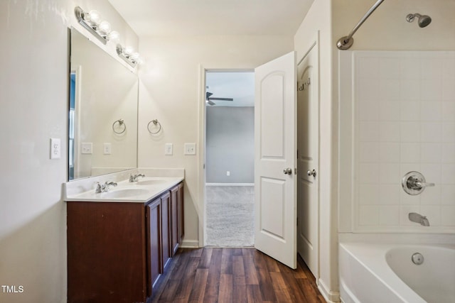 bathroom with hardwood / wood-style floors, vanity, tiled shower / bath, and ceiling fan