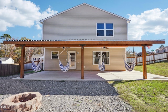 back of property featuring ceiling fan, a patio, and a fire pit