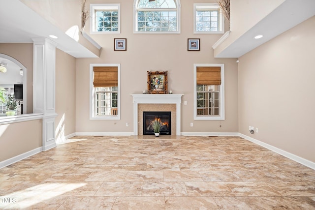 unfurnished living room with a high ceiling, ornate columns, and a wealth of natural light