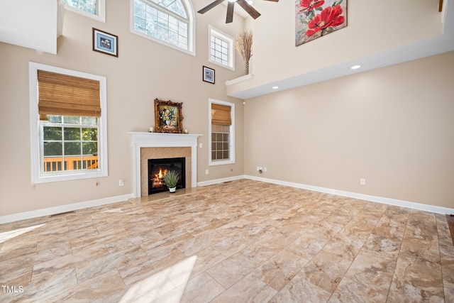 unfurnished living room featuring ceiling fan, a fireplace, and a high ceiling