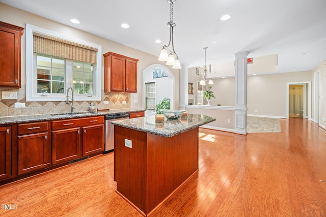 kitchen featuring pendant lighting, light hardwood / wood-style flooring, stainless steel dishwasher, ornate columns, and a kitchen island