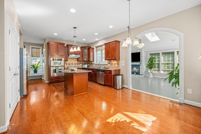 kitchen with a center island, wood-type flooring, decorative light fixtures, and appliances with stainless steel finishes