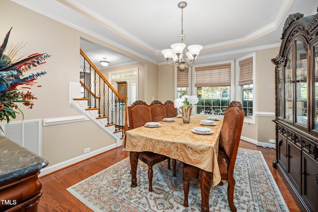 dining room with a chandelier, dark hardwood / wood-style flooring, a raised ceiling, and ornamental molding