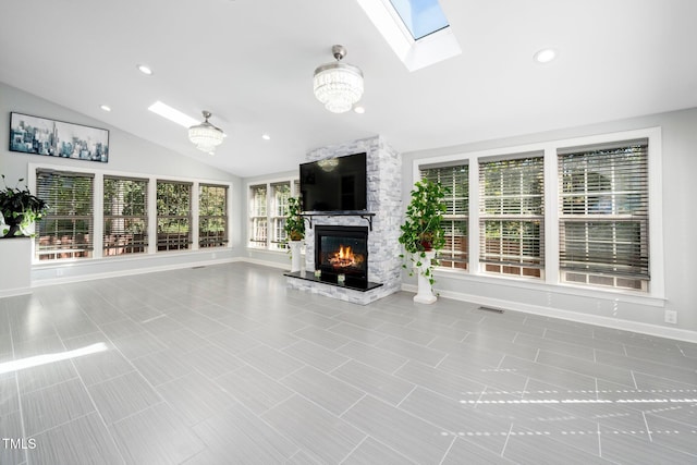 unfurnished living room with vaulted ceiling with skylight, light tile patterned floors, a fireplace, and an inviting chandelier