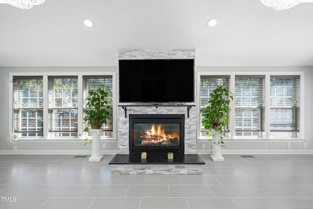 unfurnished living room featuring tile patterned floors, a stone fireplace, and a wealth of natural light