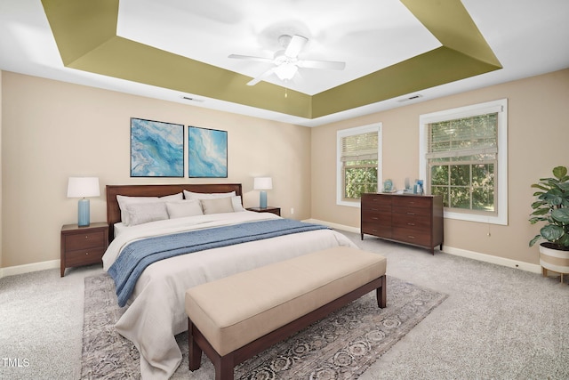 carpeted bedroom featuring a tray ceiling and ceiling fan