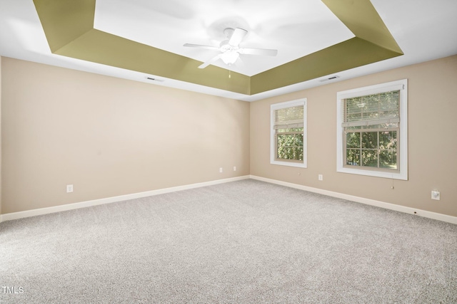 carpeted spare room featuring a tray ceiling and ceiling fan