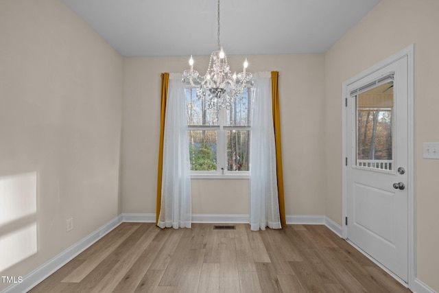 unfurnished dining area with light hardwood / wood-style floors and a chandelier