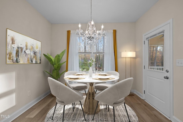 dining space with wood-type flooring and a notable chandelier