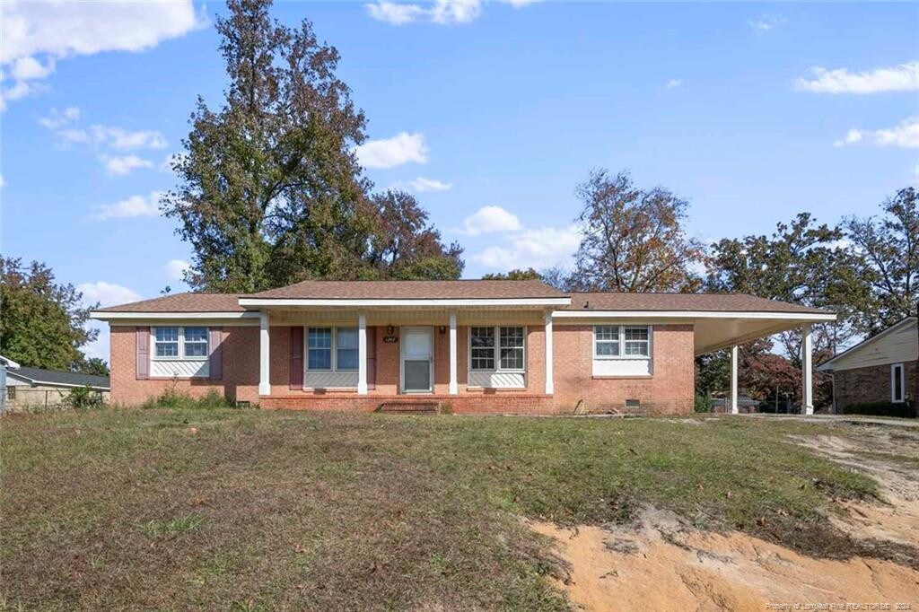 ranch-style home featuring a front yard and a carport