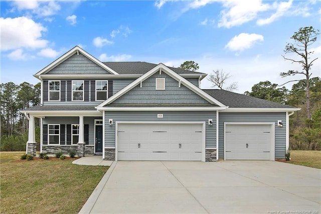 craftsman house featuring stone siding, a garage, a front yard, covered porch, and driveway