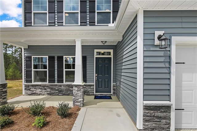 view of exterior entry featuring a porch and stone siding