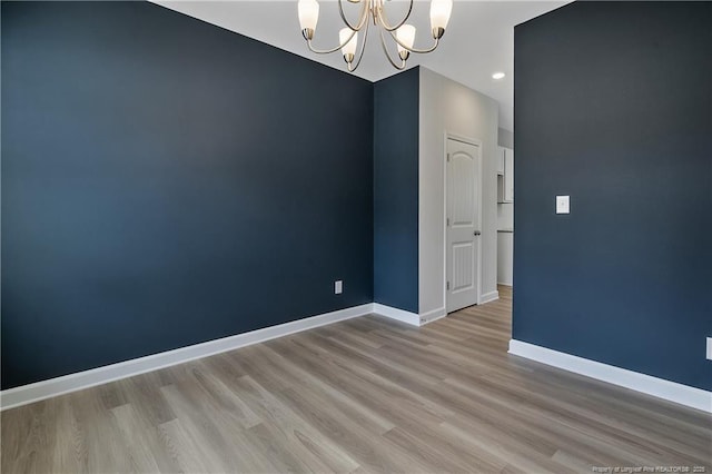 empty room with recessed lighting, baseboards, a chandelier, and wood finished floors