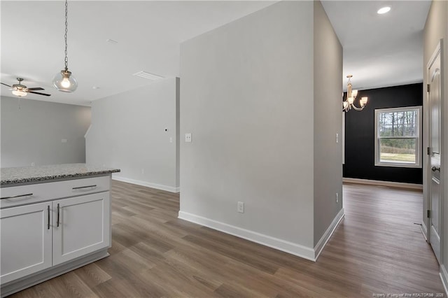 kitchen featuring baseboards, hanging light fixtures, ceiling fan with notable chandelier, and wood finished floors