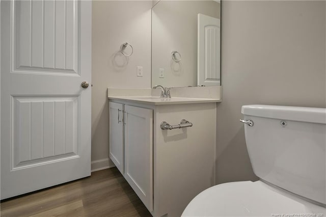 half bath featuring vanity, wood finished floors, and toilet