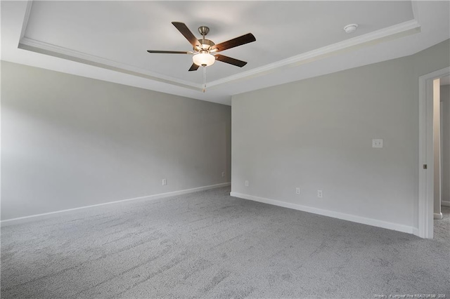 carpeted empty room featuring baseboards, a tray ceiling, ornamental molding, and ceiling fan