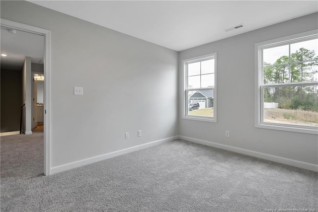 spare room with carpet floors, baseboards, and visible vents