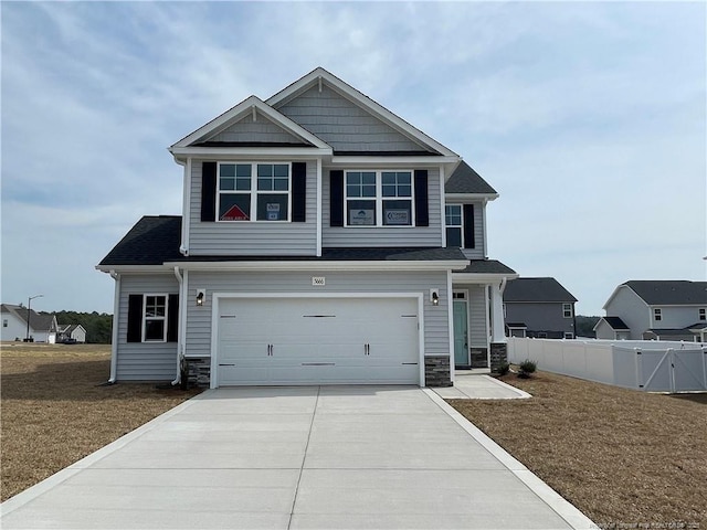 craftsman house with stone siding, concrete driveway, a garage, and fence