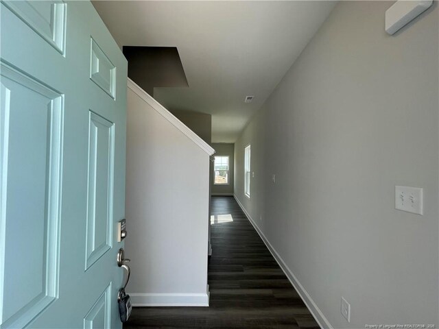 corridor with visible vents, dark wood-style floors, and baseboards